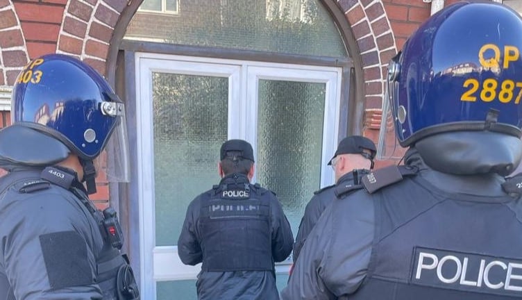 Police officers prepare to enter premises suspected to house a large cannabis grow 