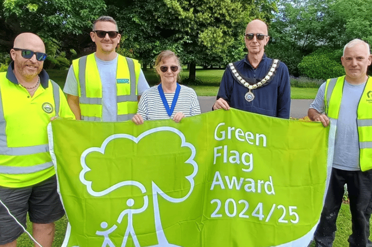 Minehead Mayor Cllr Craig Palmer and deputy mayor Cllr Anne Lawson with amenities staff and the Green Flag awarded to the town's Blenheim Gardens.