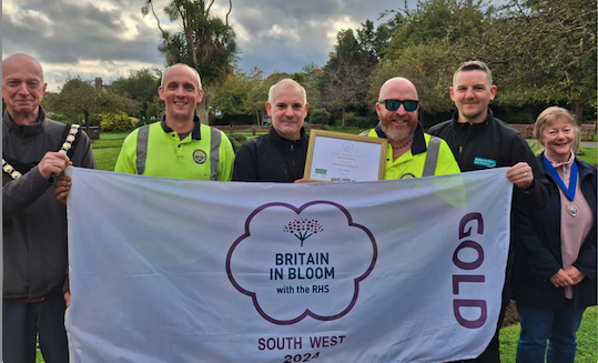 Minehead Mayor Cllr Craig Palmer and deputy mayor Cllr Anne Lawton flank staff in Blenheim Gardens celebrating the town's South West in Bloom 2024 gold award.